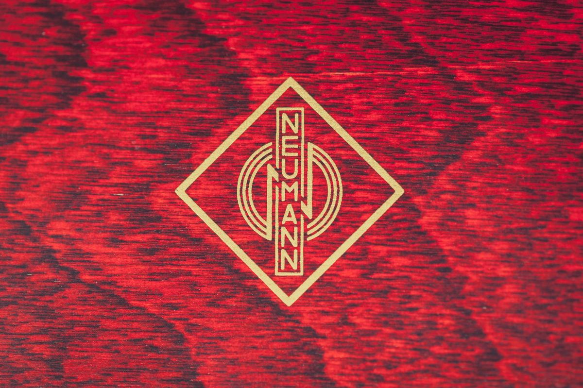 Neumann badge on a red wooden case